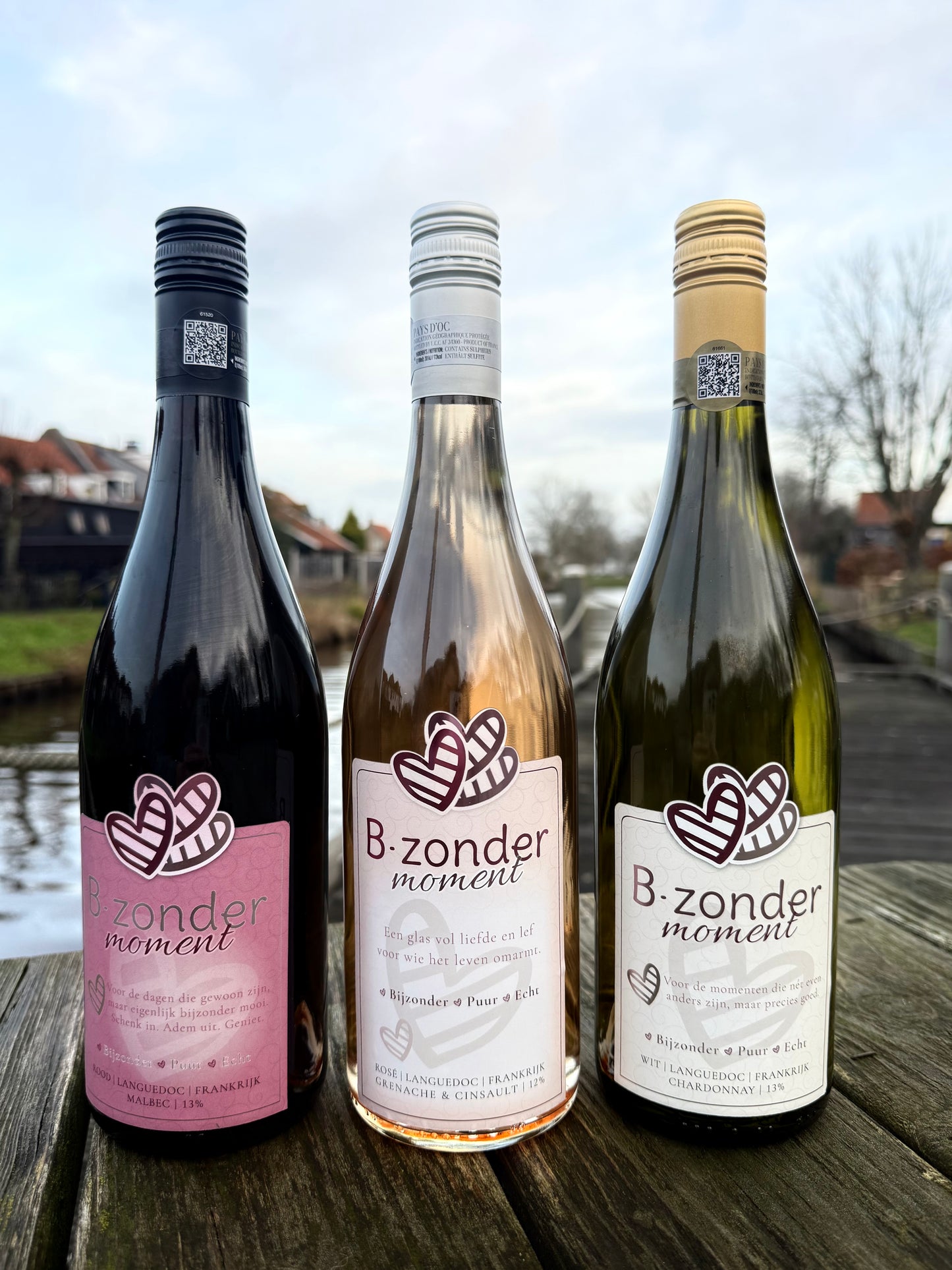 Drie flessen B.zonder moment wijn met Malbec, Rosé en Chardonnay op houten tafel buiten