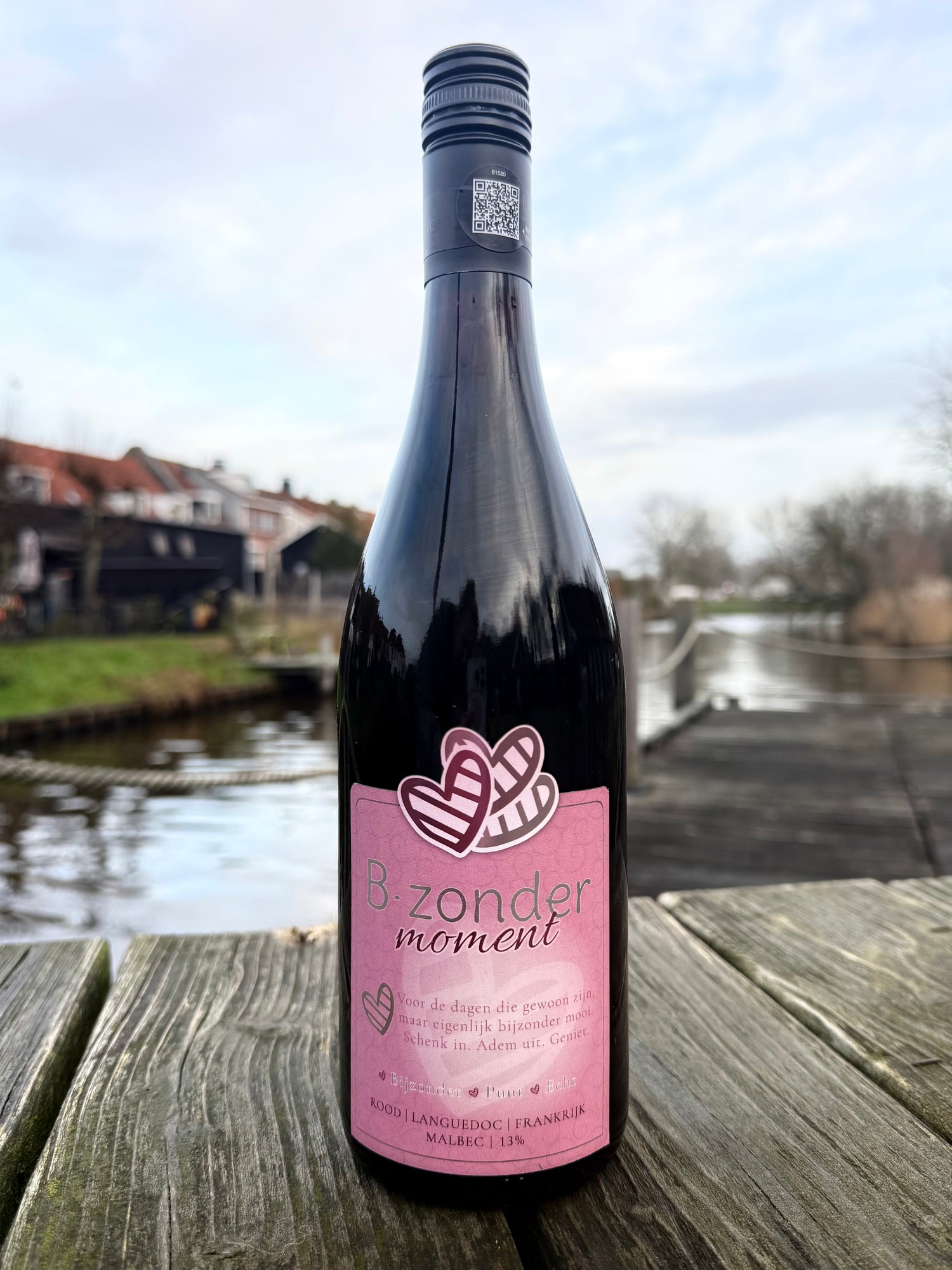 Fles B-zonder moment rode Malbec wijn uit Languedoc Frankrijk op houten tafel aan het water